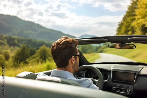 Back view of young man driving open roof convertible sports car on summer travel vacation