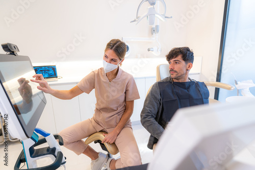 Dentist showing 3d image to patient sitting on a chair photo