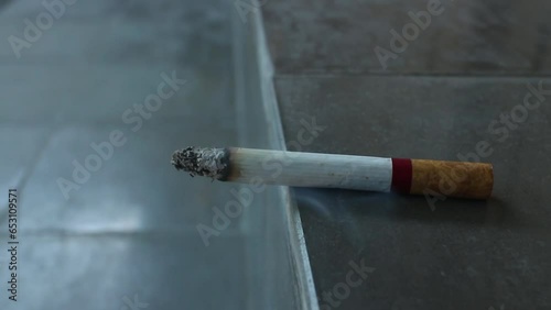 burning cigarette kretek from Indonesia on paved stair. photo