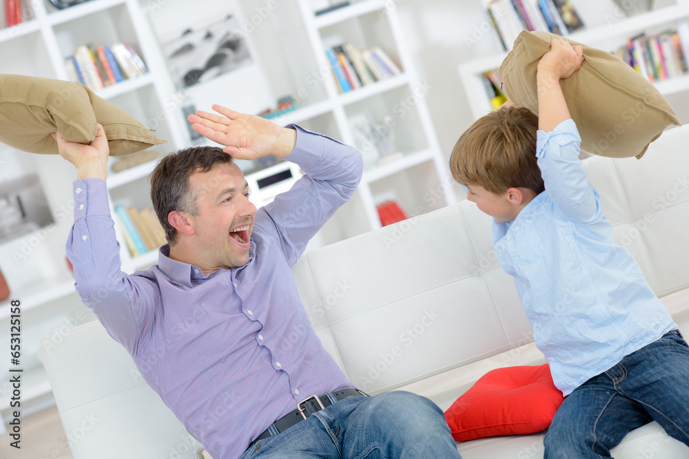 Father and son play fighting with cushions Father and son play fighting with cushions