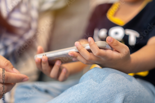 Cropped image of little boy sittiing on sofa and using mobile phone to play at home. photo