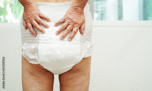Asian senior woman patient wearing adult incontinence diaper pad in hospital. photo