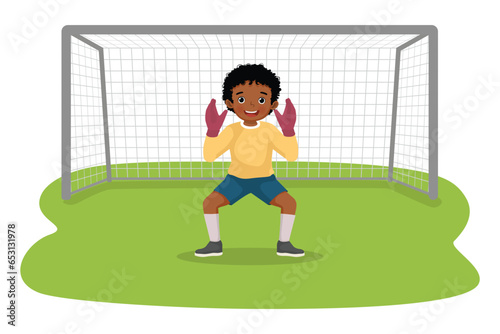 Cute little African boy playing soccer ball as a goalkeeper standing in pose at the goal