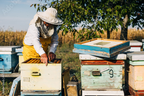 Man working outside with hives full of bees.