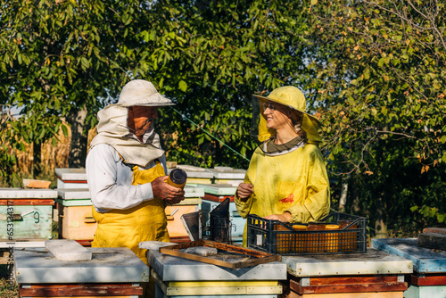 Young woman is helping her granddad stack jars of honey in a crate.