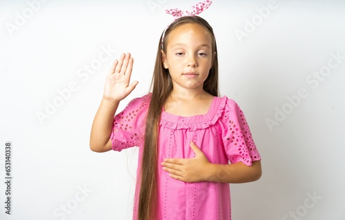 Obraz na płótnie beautiful kid girl wearing pink dress Swearing with hand on chest and open palm,