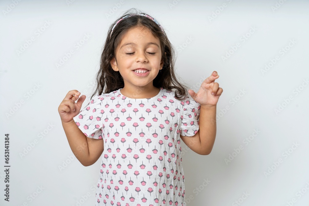 beautiful kid girl wearing dress gesturing finger crossed smiling with hope and eyes closed. Luck and superstitious concept. beautiful kid girl wearing dress gesturing finger crossed smiling with hope and eyes closed. Luck and superstitious concept.
