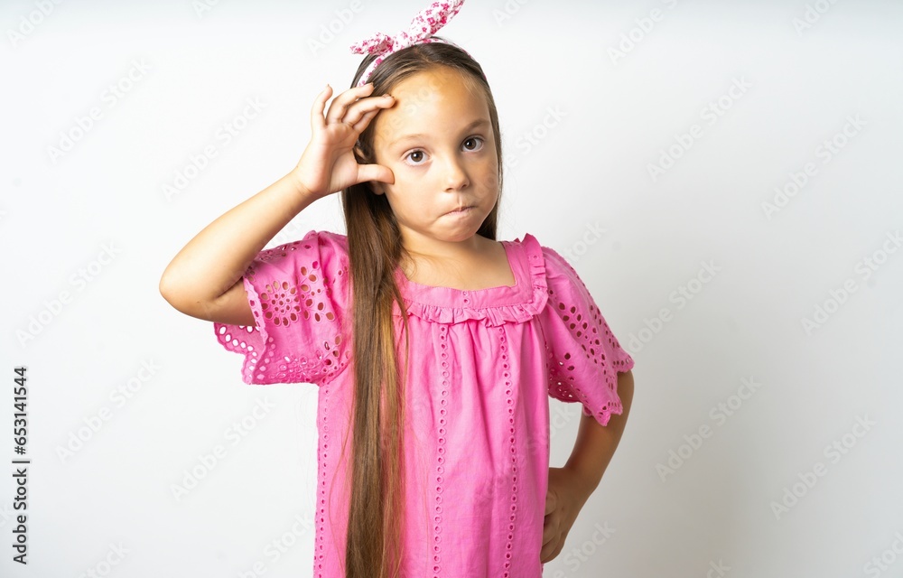 beautiful kid girl wearing pink dress having problems, worried and stressed holds hand on forehead. beautiful kid girl wearing pink dress having problems, worried and stressed holds hand on forehead.