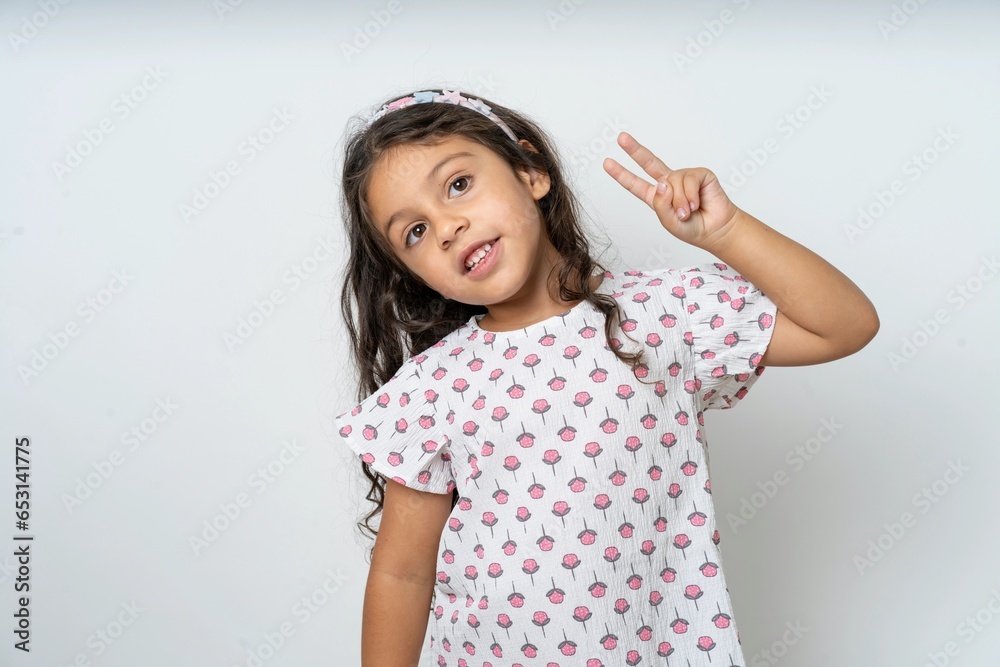 beautiful kid girl wearing dress Doing peace symbol with fingers over face, smiling cheerful showing victory beautiful kid girl wearing dress Doing peace symbol with fingers over face, smiling cheerful showing victory