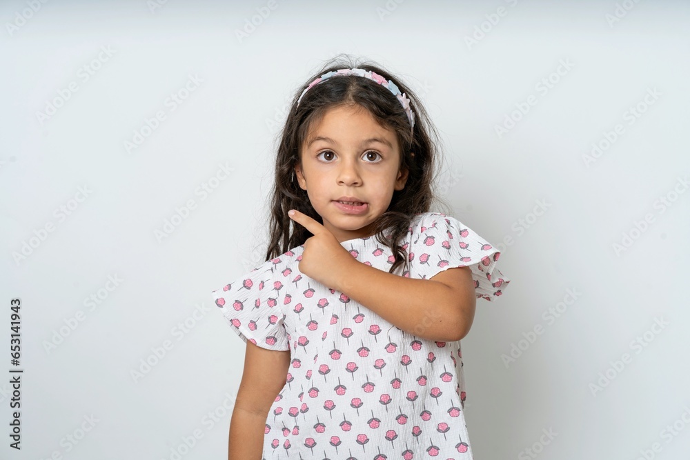 beautiful kid girl wearing dress Pointing aside worried and nervous with forefinger, concern and surprise concept. beautiful kid girl wearing dress Pointing aside worried and nervous with forefinger, concern and surprise concept.