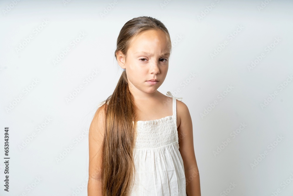 Offended dissatisfied beautiful kid girl wearing white dress with moody displeased expression at camera being disappointed by something Offended dissatisfied beautiful kid girl wearing white dress with moody displeased expression at camera being disappointed by something