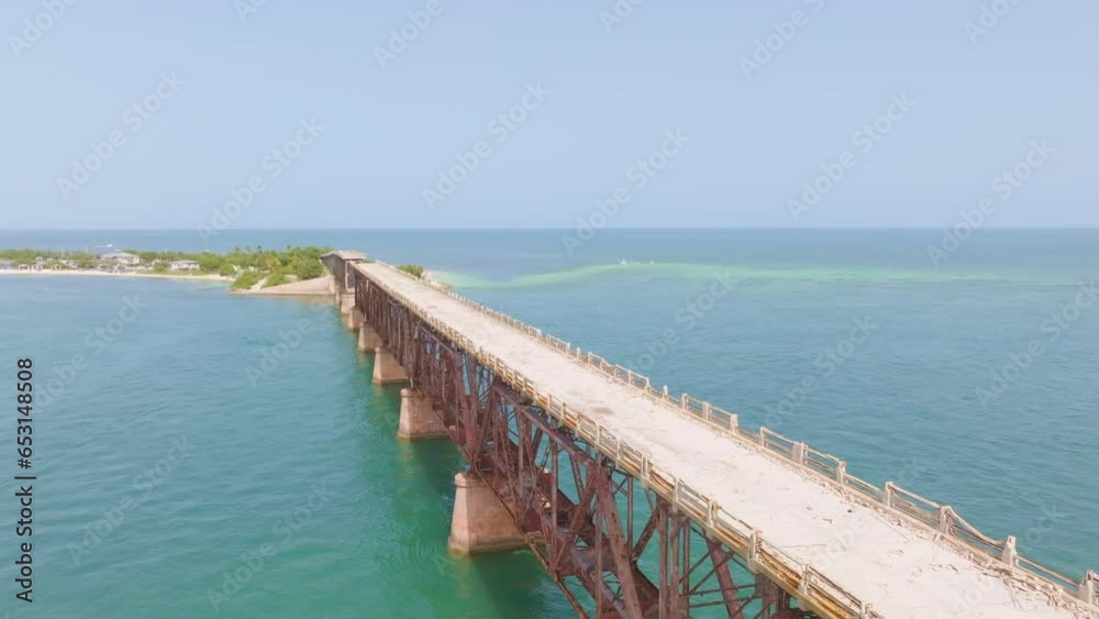 Aerial pullback along sandy broken down wooden bridge on concrete stilts in ocean Aerial pullback along sandy broken down wooden bridge on concrete stilts in ocean