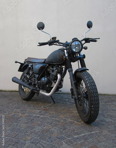 Moto classica nera opaco con rifiniture argentate  griglia sul fanale e sella in pelle ricamata stile vintage