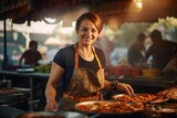 Mature woman cooking street food in a street food market, smiling and looking at camera
