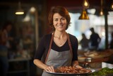 Portrait of a smiling woman standing in a cafe, holding a plate of sausages