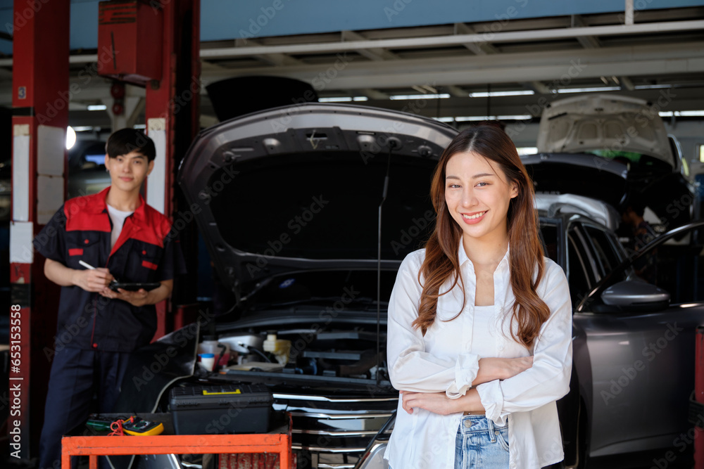 Young Asian female customer with automotive mechanic worker, arms crossed and happy smiles in quality at maintenance garage, professional vehicle service station, fix check and repair auto industry. Young Asian female customer with automotive mechanic worker, arms crossed and happy smiles in quality at maintenance garage, professional vehicle service station, fix check and repair auto industry.