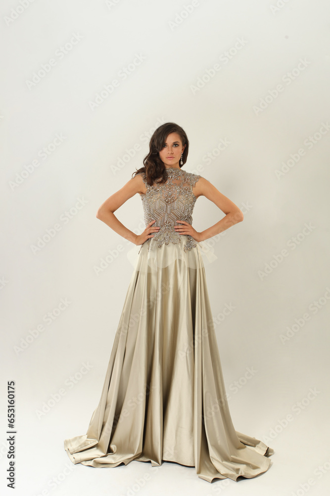 Fashionable young adult model woman in perfect silver dress standing on white background