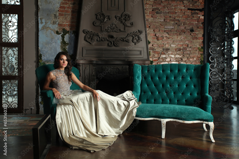 Portrait of beautiful magnificent fashion model woman wearing fashionable silver evening gown posing in vintage palace interior Portrait of beautiful magnificent fashion model woman wearing fashionable silver evening gown posing in vintage palace interior