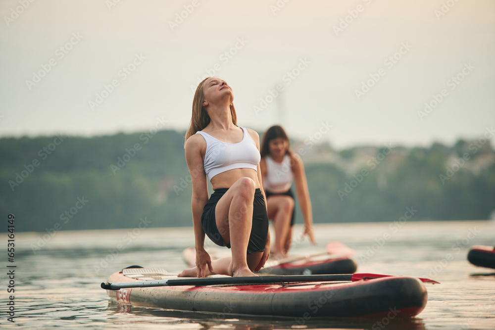 Young women are on sup boards in the lake