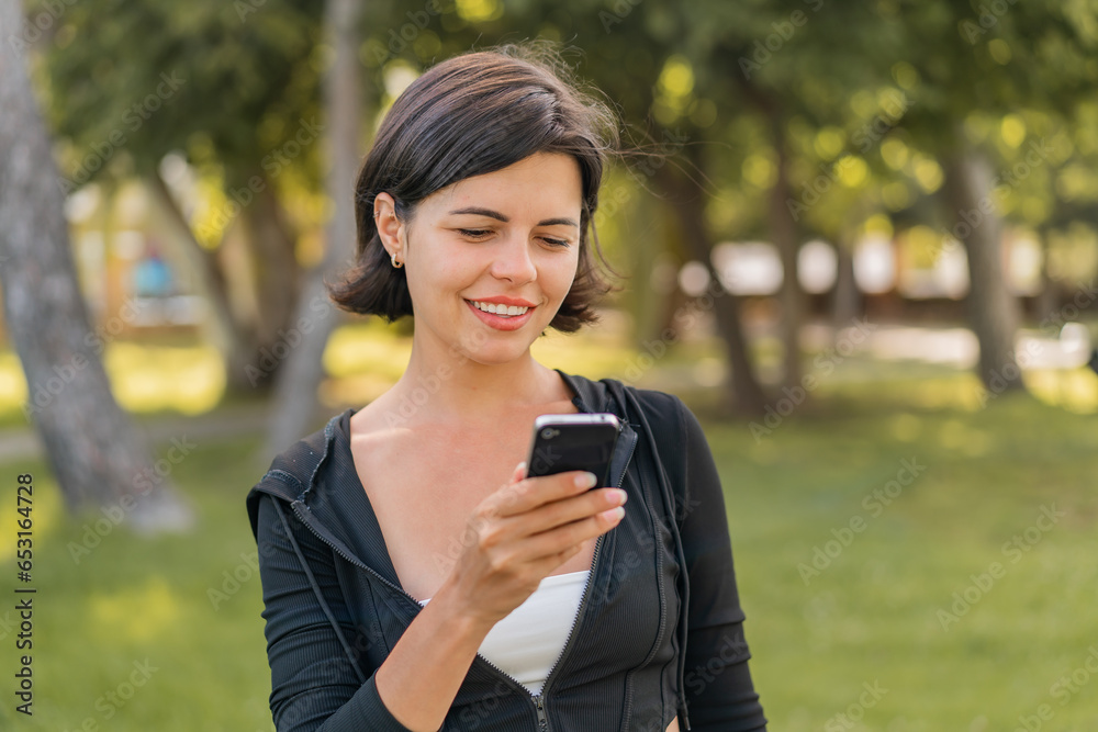Young pretty Bulgarian woman at outdoors sending a message or email with the mobile Young pretty Bulgarian woman at outdoors sending a message or email with the mobile