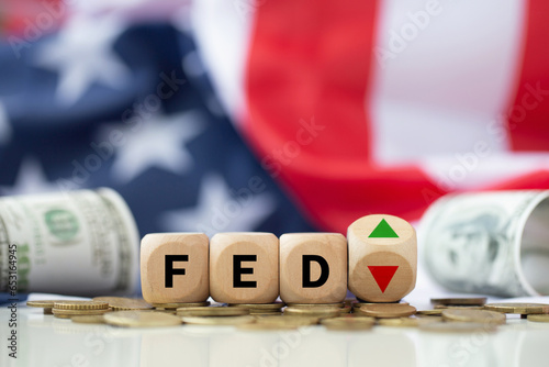 The Federal Reserve ( FED ) to control interest rates. Wooden blocks FED on coins with USA flag background. American economy and business. Federal Reserve Bank Interest rates rise policy. FED concept. photo