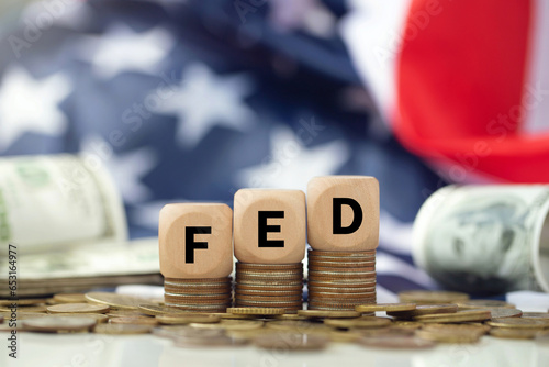 The Federal Reserve ( FED ) to control interest rates. Wooden blocks FED on coins with USA flag background. American economy and business. Federal Reserve Bank Interest rates rise policy. FED concept. photo