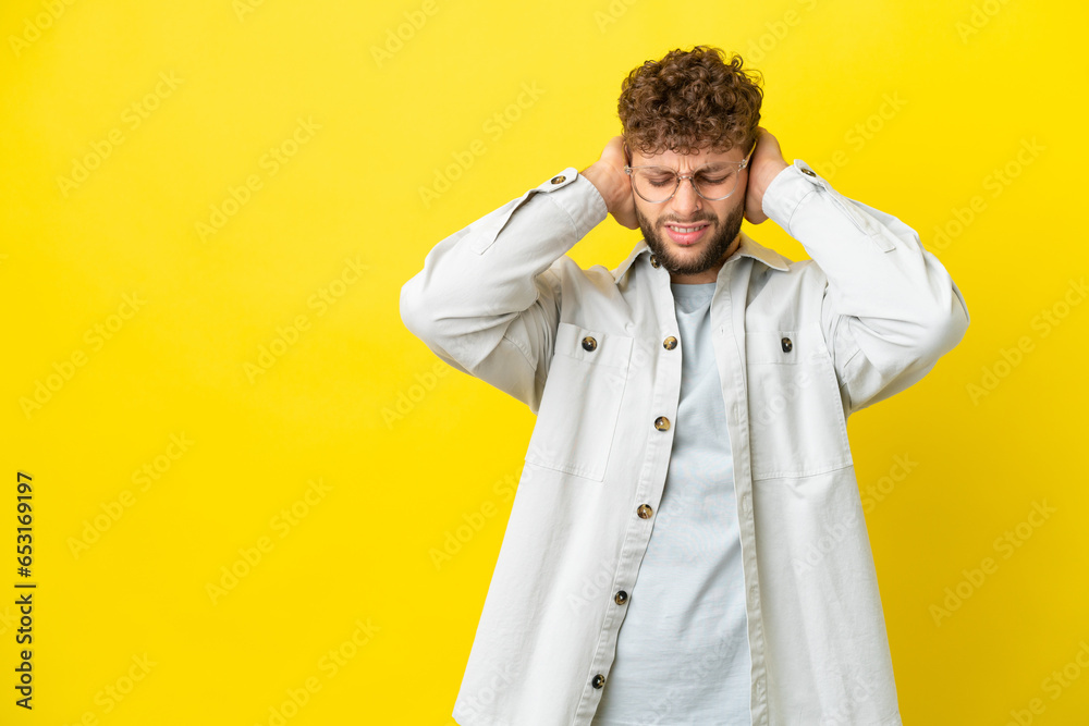 Young handsome caucasian man isolated on yellow background frustrated and covering ears Young handsome caucasian man isolated on yellow background frustrated and covering ears