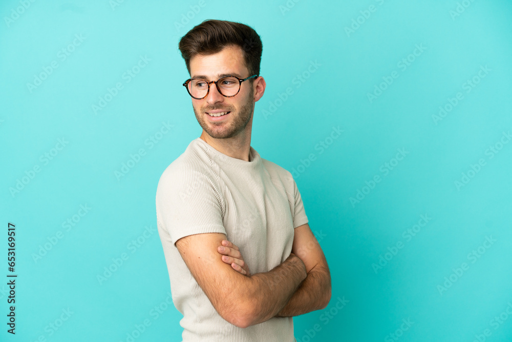 Young caucasian handsome man isolated on blue background looking to the side and smiling Young caucasian handsome man isolated on blue background looking to the side and smiling
