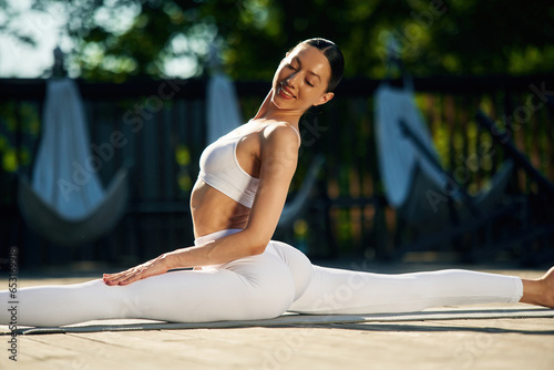 Strength and flexibility. Young woman in yoga clothes is outdoors photo