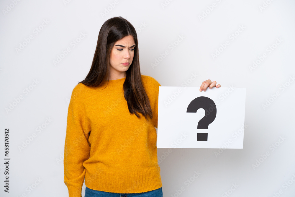 Young Brazilian woman isolated on white background holding a placard with question mark symbol Young Brazilian woman isolated on white background holding a placard with question mark symbol