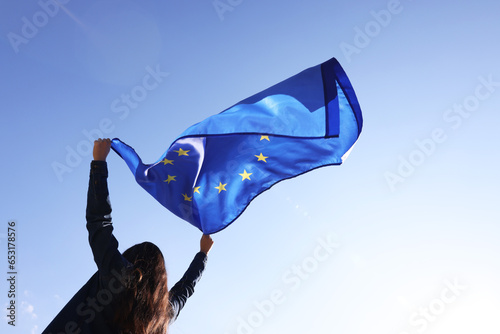 Woman holding European Union flag against blue sky outdoors, low angle view photo