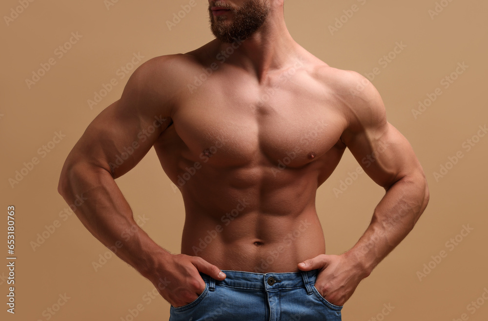 Muscular man showing abs on beige background, closeup. Sexy body