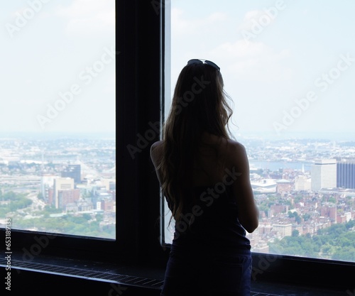 A girl looks out the window at the panorama of the city of Boston. Silhouette of a girl photo