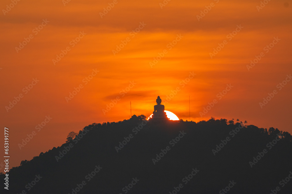 .The sun circles in the orange sky behind the Big Buddha..Amazing Phuket big Buddha in circle of the sun in yellow sky..The beauty of the statue fits perfectly with the charming nature.