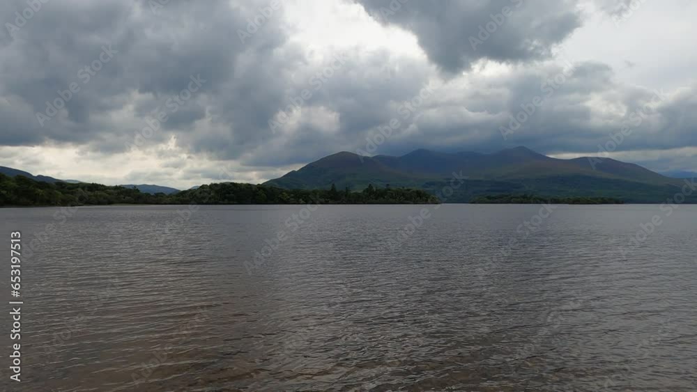 Lake side rolling mountain landscape under heavy overcast cloud Lake side rolling mountain landscape under heavy overcast cloud