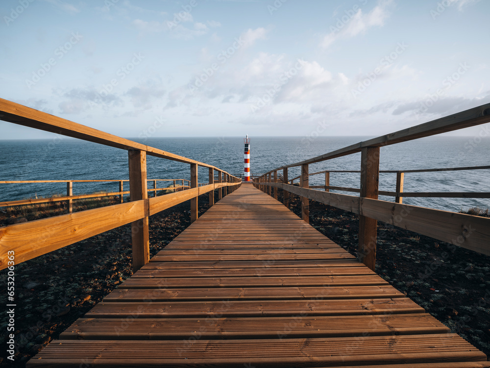 Farolim dos Fenais da Ajuda lighthouse with a symmetrical wooden path leading to it, Sao Miguel island, Azores Islands, Portugal, Atlantic Farolim dos Fenais da Ajuda lighthouse with a symmetrical wooden path leading to it, Sao Miguel island, Azores Islands, Portugal, Atlantic