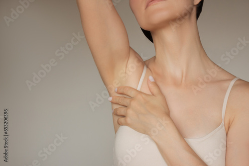 photo of a pretty young Caucasian woman in beige underwear gently touching her smooth body after epilation of armpits. Shaving and epilation of the body.