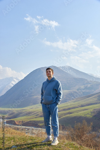 teenager against the backdrop of the mountains after climbing portrait of a cheerful boy in the highlands