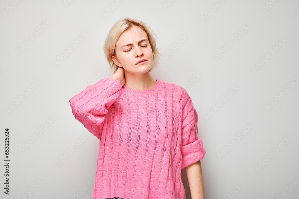 Portrait of young woman suffering from pain, touching neck isolated on white studio background. Psychosomatics of stress, degenerative disease of spine Portrait of young woman suffering from pain, touching neck isolated on white studio background. Psychosomatics of stress, degenerative disease of spine