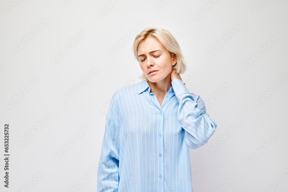Portrait of young woman suffering from pain, touching neck isolated on white studio background. Psychosomatics of stress, degenerative disease of spine Portrait of young woman suffering from pain, touching neck isolated on white studio background. Psychosomatics of stress, degenerative disease of spine
