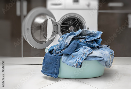 Basket with dirty jeans near the washing machine.