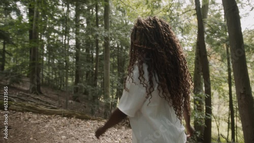 Following from behind a young adult black woman hiking through the woods in northern Michigan. photo