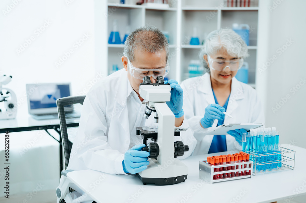 Two scientist or medical technician working, having a medical discuss meeting with Asian senior female scientist supervisor in the laboratory with online reading, test samples and innovation Two scientist or medical technician working, having a medical discuss meeting with Asian senior female scientist supervisor in the laboratory with online reading, test samples and innovation
