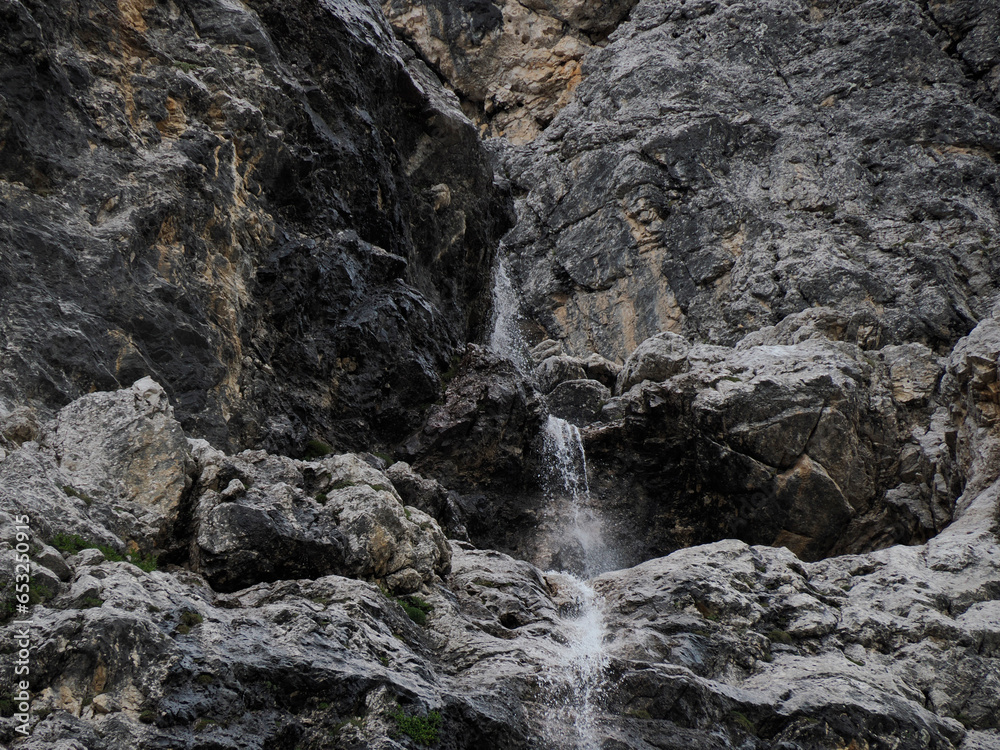 small waterfall on detail of rock of monte croce cross mountain in dolomites badia valley panorama landscape