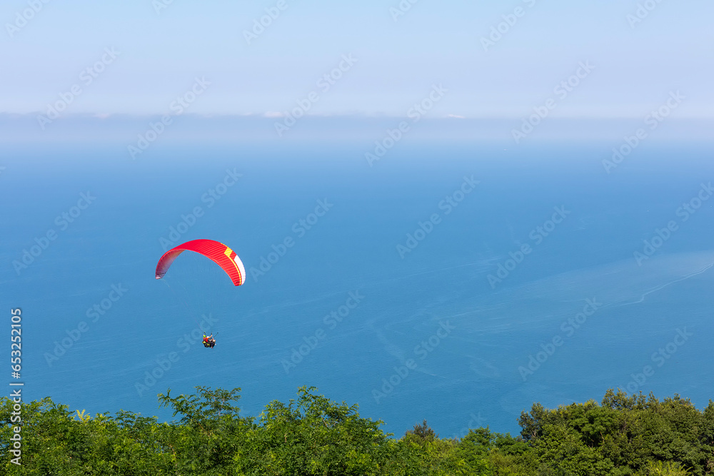 Paraglider in the blue sky and sea. The sportsman flying on a paraglider. Paraglider in the blue sky and sea. The sportsman flying on a paraglider.
