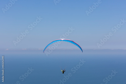 Paraglider in the blue sky and sea. The sportsman flying on a paraglider.