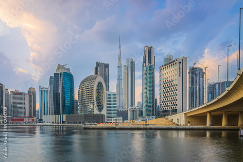 financial district of Dubai. City sunset skyline. Business center with office buildings and skyscrapers around Burj Khalifa. Street with a bridge over the harbor in the evening mood