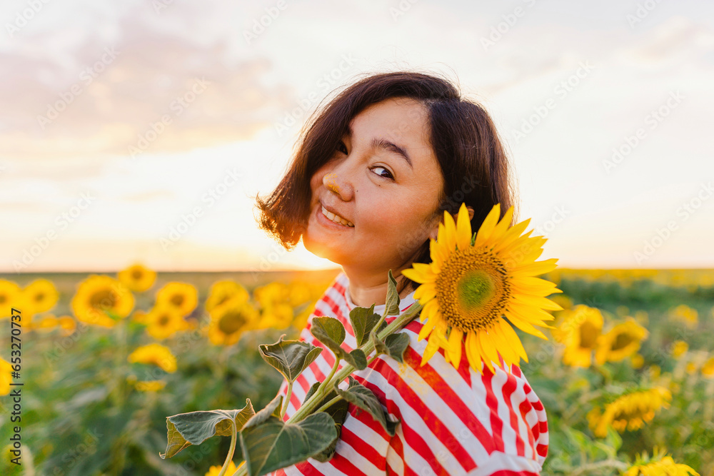 Mature smiling woman with sunflower at sunset Mature smiling woman with sunflower at sunset