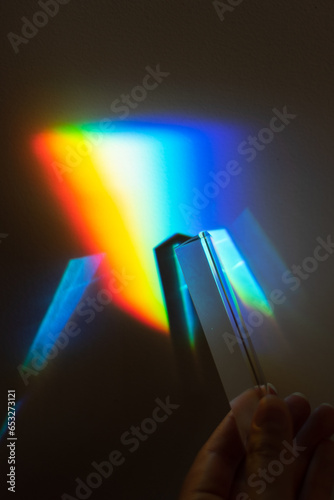 hand holding a prism rainbow effect on a wall colorful light science 