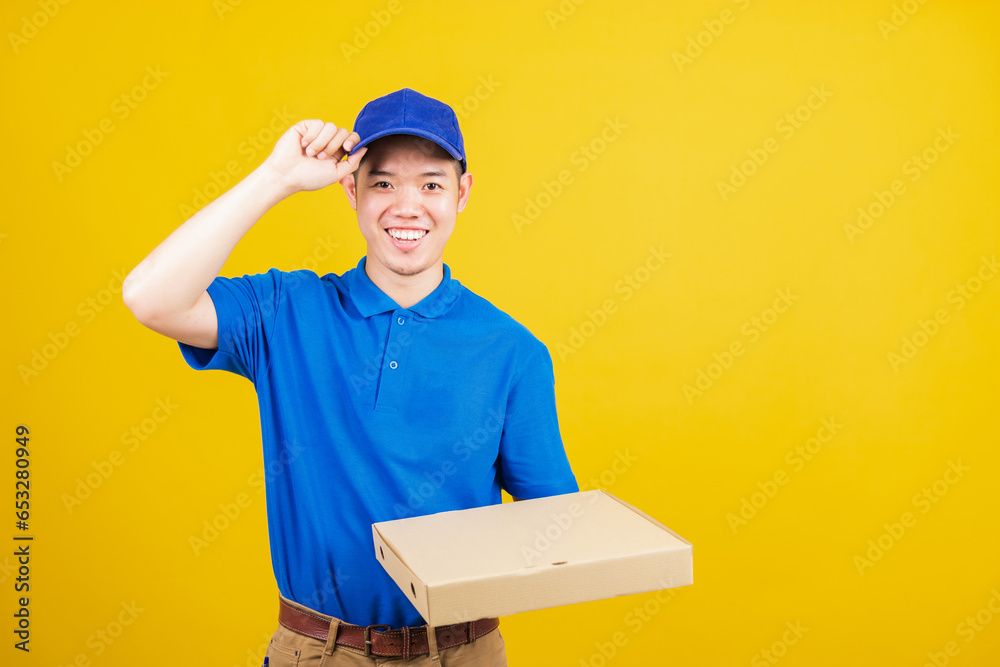 Portrait excited delivery service man standing he smile wearing blue t-shirt and cap uniform hold give food order pizza cardboard boxes looking to camera, studio shot isolated on yellow background Portrait excited delivery service man standing he smile wearing blue t-shirt and cap uniform hold give food order pizza cardboard boxes looking to camera, studio shot isolated on yellow background